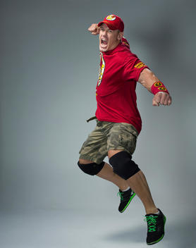 Wrestler John Cena jumps up in the air, shouting and his hand ready to punch