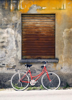 a red bike resting against a distress wall