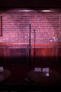 microphone on stand in front of brick wall in comedy club
