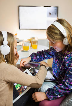 Sisters listening music on digital tablets in living room