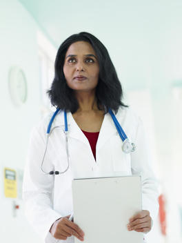 Indian doctor in lab coat holding medical chart