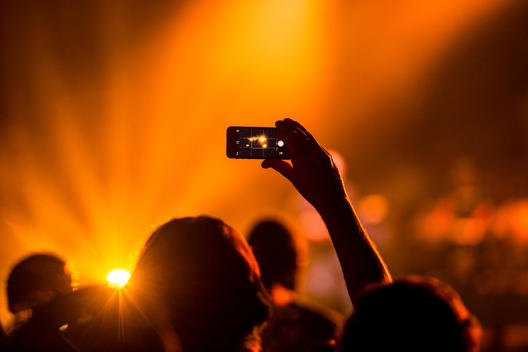 A person holding up an phone taking pictures at a concert.