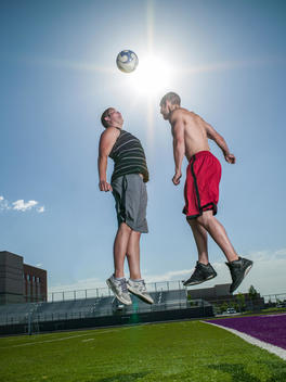 Two young men with soccer ball on sports field