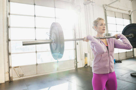 Woman practicing clean and jerks in Crossfit gym
