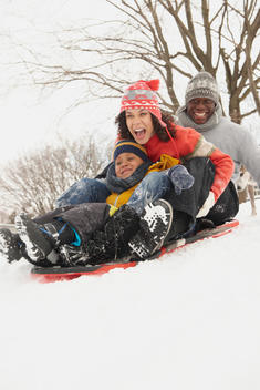 Black family sledding in snow