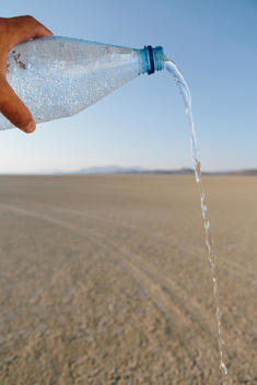 The Landscape Of The Black Rock Desert In Nevada. A Bottle Of Water Being Poured Out. Filtered Mineral Water.