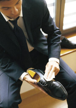 Man in suit polishing shoe, close-up