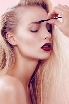 Closeup up of blonde model in bare skin and light natural makeup with red lips