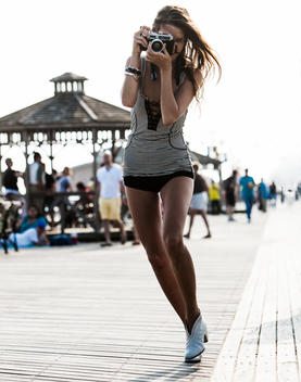 woman on boardwalk taking photo with vintage camera