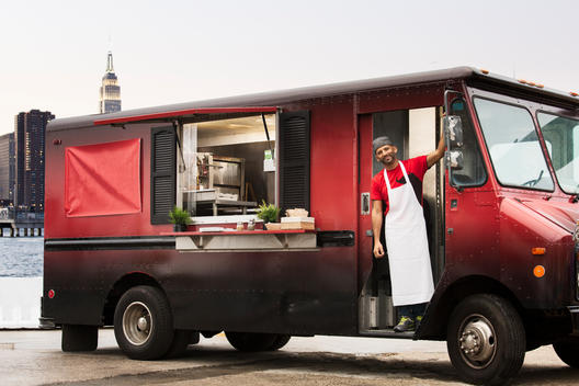 Small business owner inside his Food Truck facing the camera with Manhattan in the background