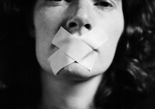 Woman with tape over mouth, close-up, blurred