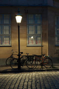 Bicycles Parked Under A Street Lamp At Night