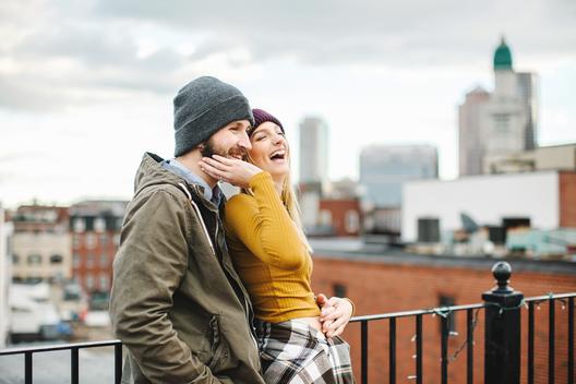 Young couple laughing on city rooftop terrace