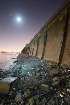 The embankment of the River Thames at night with a full moon near the Thames Barrier