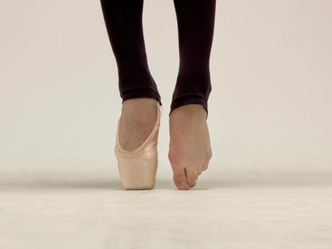 Close-up of Female Ballet dancer\'s feet on pointe with one shoe on
