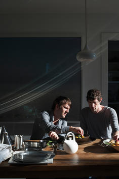 Chefs Ren_ Redzepi and Daniel Patterson testing a new recipe at a wooden table
