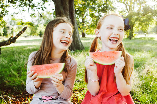 two girls eating melon laughing