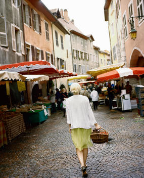 A woman walking with her shopping basket through the farmers market stands in Annecy, France.