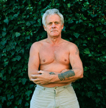 Old Man, No Shirt On, Bare Chest, And Tattoos, Muscles And Ageing Body, Sad, Defiant, Defensive.