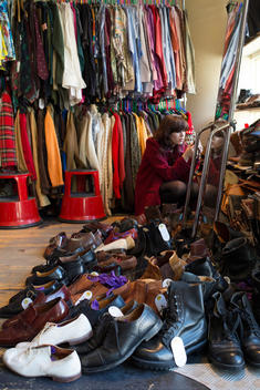 A young woman shopping in a used clothing store with leather shoes