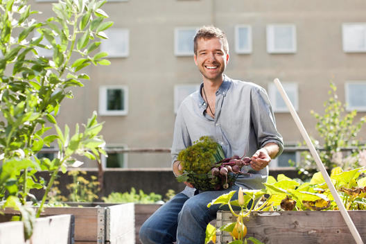 Portrait of happy young man sitting at urban garden
