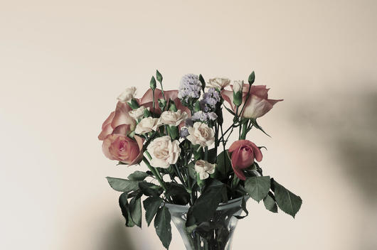 Boquet Of Pink, Cream, Violet Coloured Flowers Against An Off White Background.