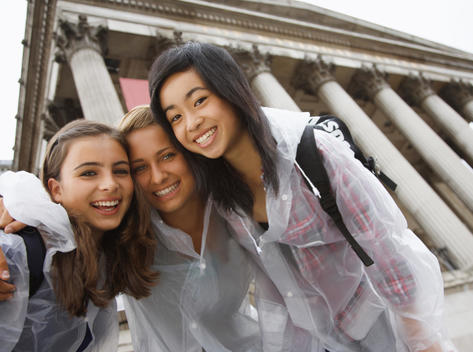 Three teenaged girls posing and smiling in front of London National Gallery