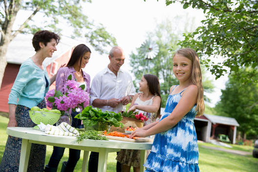 Family Party. A Table Laid With Salads And Fresh Fruits And Vegetables. Parents And Children. Two Girls, One Young Woman And A Mature Couple.