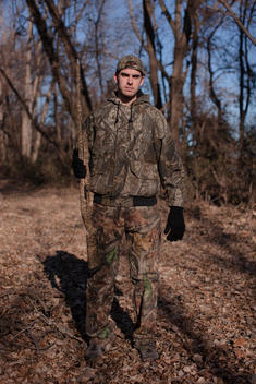 A hunter poses for a photograph in full camouflage attire.
