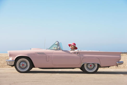 Senior woman driving pink convertible