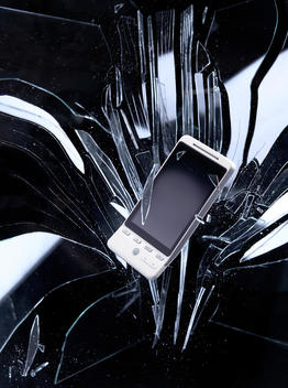 Mobile Phone Falling Through A Plate Of Glass, Surrounded By Glass Shards