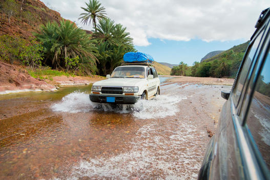 Cars driving in shallow river in tropical landscape