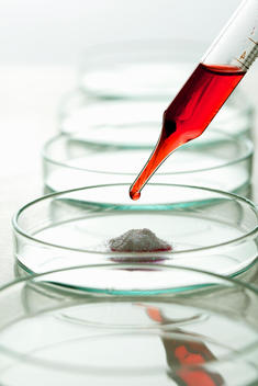 Pipette with Red Solution over Petri Dish and Pile of Powder