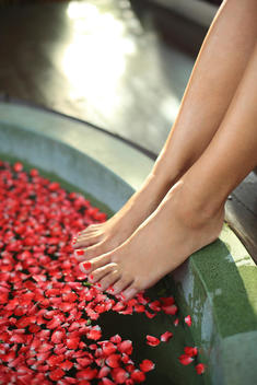 Woman\'s feet on edge of spa bath with flower petals