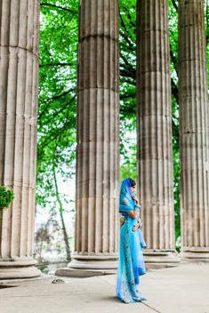 Roman architecture with the Indian bride in the foreground in a blue lengha