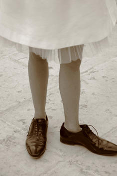 Low section of woman wearing white dress and male shoes