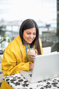 Businesswoman using laptop while having milkshake at cafe
