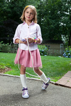 Vertical Shot Of Girl In Pink Skirt Looking At The Camera Holding A Jump Rope