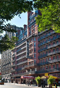 Side View, Sunny Exterior Of The Chelsea Hotel In Full Sun With Surrounding Trees. W 23Rd Street Between 6Th And 7Th Avenues Chelsea, New York, New York.