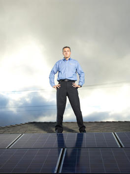 Founder of SolarCity, Lyndon Rive, stands with his hands on his hips on top of a roof covered in solar panels