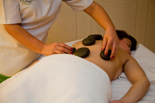 Woman is getting a treatment by round stones on her back in a luxury hotel spa in Turkey.