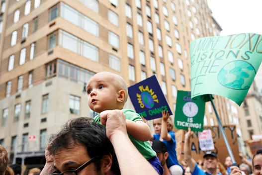 baby and father holding a banners pro environment at the climate march