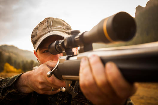 Close up shot of rifle hunter looking through scope of his gun