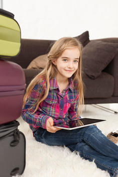 Germany, Leipzig, Girl using digital tablet and with suitcase, smiling, portrait