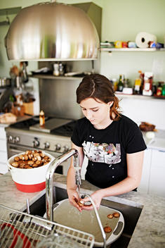 girl washing mushroom in a kitchen sink