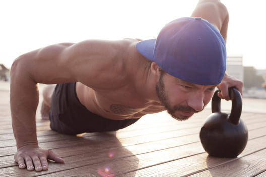 Man doing pushups with a kettle bell