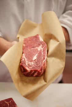 Butcher holding up a cut fresh steak.