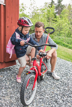 Father assisting daughter in riding bicycle