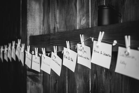 papers with the name of the guests on a line, little rose, handwritten, wooden wall