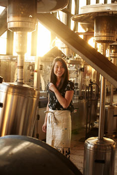 A woman indoors at sunset, wearing an apron, at a warehouse restaurant.